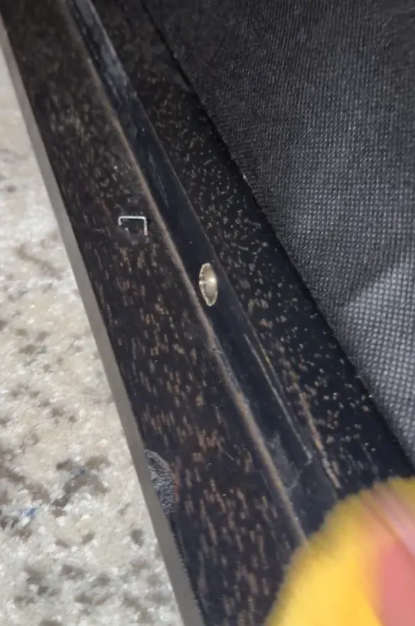 Cleaning cloth wiping the wooden frame of a sofa during a deep clean